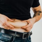 Man holding belly fat illustration of best way to lose fat and weight